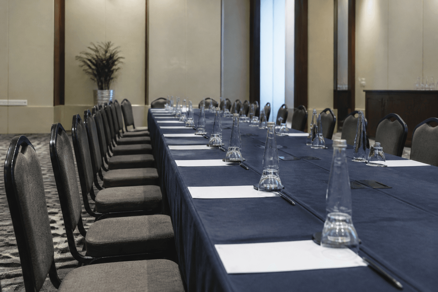Empty chairs around a long conference table in a hotel meeting room before the morning session of international trade talks.